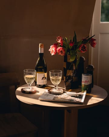 A beautifully composed, atmospheric lifestyle shot featuring a table set for two with white wine and a tin of olives, bathed in warm, golden-hour light. The image evokes a sense of relaxation and luxury, typical of a high-end hotel or aparthotel stay.