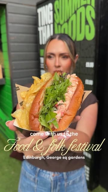 A person holds a lobster roll and chips at the Edinburgh Food & Folk Festival, promoting the event's street food offerings.