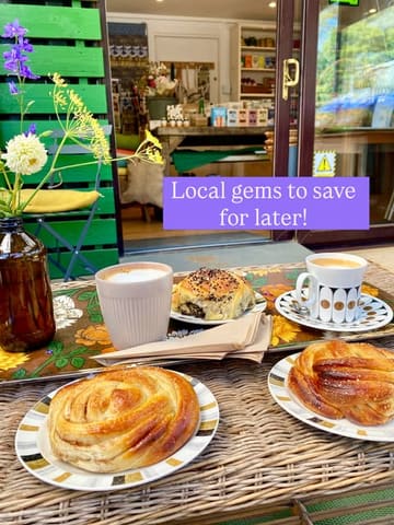 A cozy, rustic flat-lay shot of coffee and pastries, including cinnamon rolls and cheese and olive acma, set on a tray against an outdoor cafe backdrop with flowers, capturing a relaxed, local cafe vibe.