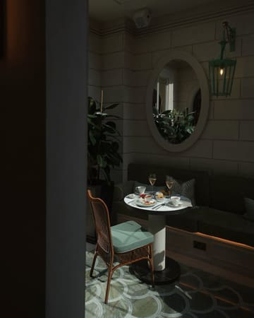 A moody, atmospheric shot of an afternoon tea service at Aki London, featuring a table set with various Japanese-inspired pastries and sandwiches. The lighting is dramatic and intimate, highlighting the elegant presentation of the food against a dark, sophisticated interior.