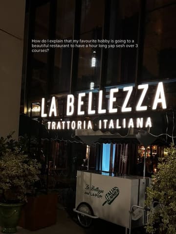 A night-time exterior shot of the restaurant La Bellezza, featuring the illuminated signage and a branded cart, accompanied by a text overlay about enjoying a long lunch.
