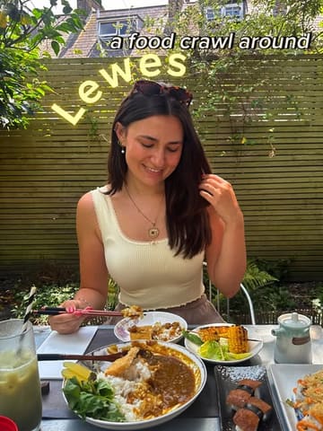 A bright, outdoor shot of a person enjoying a Japanese-inspired meal, likely part of a food crawl, featuring katsu curry and sushi.