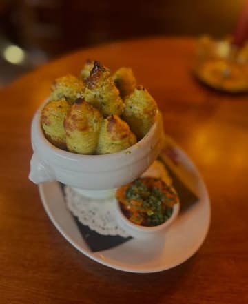 A moody, close-up shot of a Keema Shepherd's Pie served in a traditional lion-head tureen, accompanied by a side of carrot pickle, capturing the atmospheric vibe of a pub.