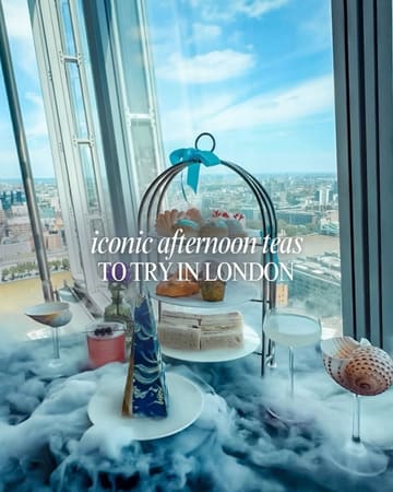 A high-angle shot of an afternoon tea service featuring a tiered stand, cocktails, and dry ice, set against a panoramic London skyline view.