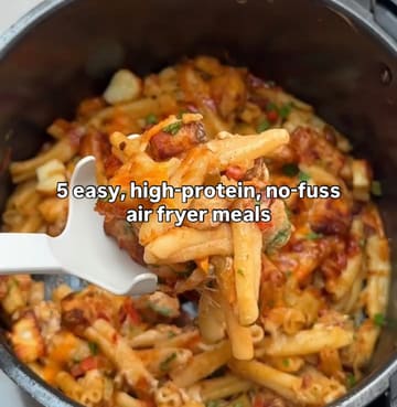 A close-up shot of a pasta dish being lifted from an air fryer basket with a white spoon, featuring text overlay about high-protein air fryer meals.