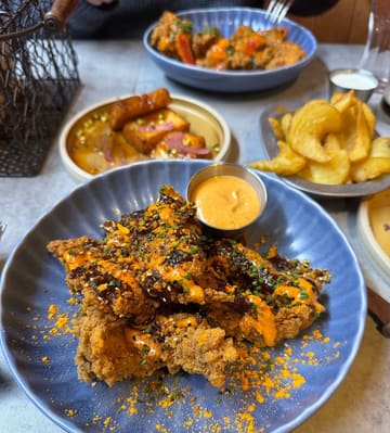 A high-angle, appetizing shot of a table spread featuring loaded chicken strips, halloumi bites, and fries at a restaurant.