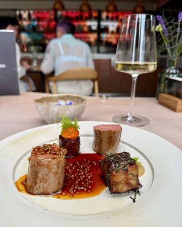 A beautifully captured, high-end plated dish featuring precision-cooked meat, likely from a tasting menu at a Michelin-starred restaurant. The composition highlights the textures and presentation of the food, with a shallow depth of field that draws the eye directly to the main elements.