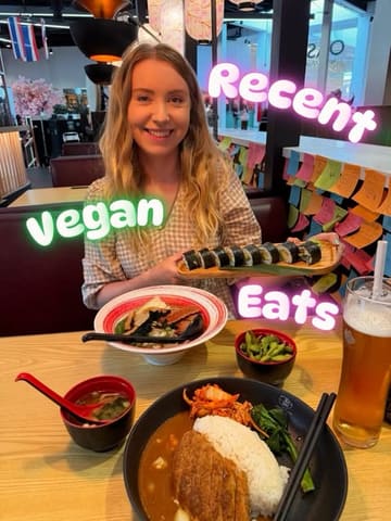 A personal, casual photo of a person holding a plate of vegan sushi, with a bowl of ramen and edamame on the table in front of them. The image is a typical 'what I ate' style post, capturing a meal out.