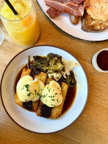 A high-quality, overhead food photography shot featuring a breakfast dish of ox cheek hash with poached eggs and hollandaise, served at The Metropolitan in Bristol.
