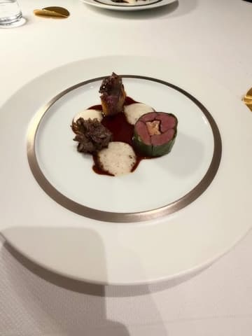 A high-quality, minimalist photograph of a fine dining venison dish served at Solstice in Newcastle. The plating is precise and elegant, set against a clean white tablecloth, highlighting the sophisticated nature of the meal.