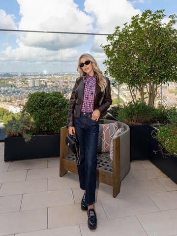 A lifestyle and fashion-focused image featuring a creator posing on a terrace at the Park Hyatt Residences, highlighting the city skyline view.
