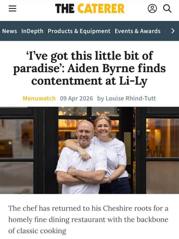 A professional portrait of chef Aiden Byrne and his partner Sarah Byrne, taken for a feature in The Caterer magazine about their restaurant, Li-Ly. The image conveys a warm, welcoming atmosphere suitable for a fine dining establishment.