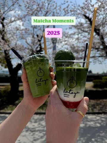 A bright, well-composed shot of two matcha drinks held up against a scenic background of cherry blossoms and the Tokyo Skytree. The image effectively captures a 'matcha moment' with clear focus on the products, highlighting the vibrant green color of the drinks.