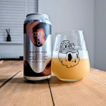 A clean, well-composed product shot featuring a can of 'Repertoire' DIPA by Track Brewing Co alongside a glass of the poured beer, set against a simple, neutral background.