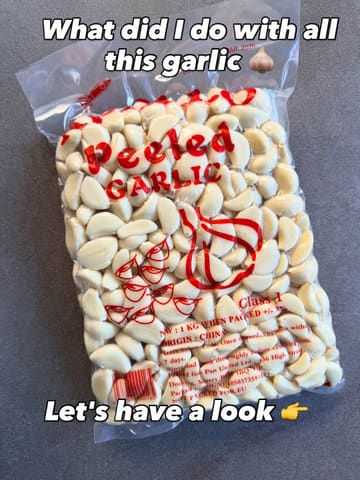 A clear, top-down, well-lit photograph of a 1kg bag of peeled garlic cloves resting on a neutral grey surface. The image serves as a teaser for a home cooking project, utilizing text overlays to engage the audience.
