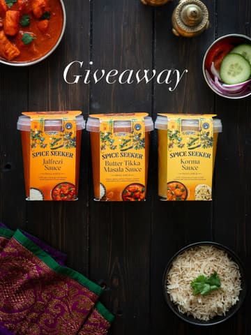 A professional, high-quality flat-lay photograph promoting a range of 'Spice Seeker' Indian sauces. The image features three plastic tubs of sauce (Jalfrezi, Butter Tikka Masala, Korma) arranged symmetrically on a dark wooden surface, accompanied by bowls of rice and salad, and a decorative textile. The composition is clean, balanced, and visually appealing, effectively showcasing the product for a giveaway promotion.