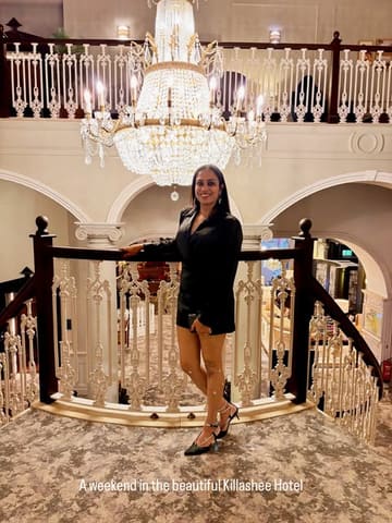 A photo of a woman posing on a grand staircase in a hotel lobby, showcasing the venue's interior architecture.