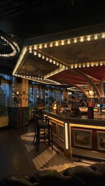 A wide-angle, atmospheric shot of the interior of Flight Club Victoria, focusing on the bar area with its signature decorative bulb lighting and moody, inviting aesthetic.