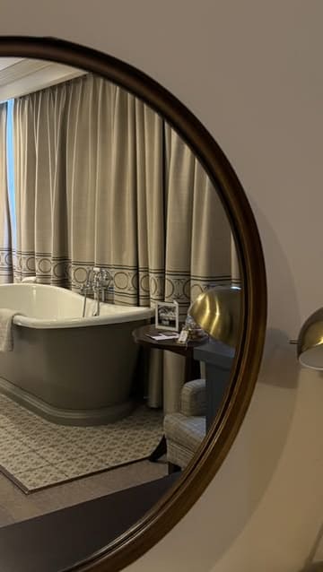 A photo taken through a circular mirror showing a hotel room with a freestanding bathtub, highlighting the elegant and homely interior of a Georgian Deluxe room at a hotel in Richmond.