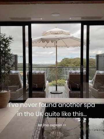 A high-quality, atmospheric shot of a spa pool looking out onto a scenic, green landscape through large glass doors. The image effectively uses natural light to create a relaxing, luxurious mood, inviting the viewer to experience the venue.