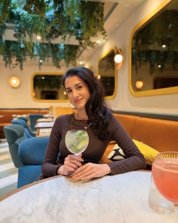A high-quality, well-composed portrait of a customer enjoying a cocktail at Dottie's Restaurant, highlighting the venue's modern, inviting interior and relaxed atmosphere.