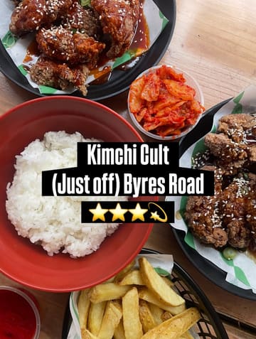 A flat-lay photograph of a Korean fried chicken meal, including rice, kimchi, and chips, served in casual takeaway-style containers on a wooden table.