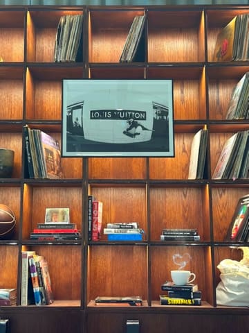 A static, atmospheric shot of a coffee cup placed on a wooden bookshelf, intended to showcase the interior aesthetic of a coffee shop.