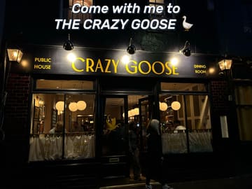 A night-time exterior shot of 'The Crazy Goose' pub and dining room in Brighton. The image captures the storefront with warm lighting, clear signage, and patrons visible through the windows, creating an inviting atmosphere.