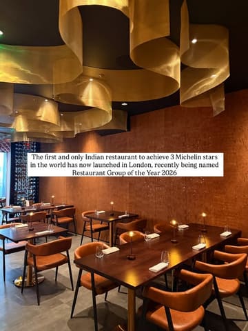 A professional, wide-angle interior shot of a high-end restaurant dining room, featuring warm ambient lighting, modern decor with gold ceiling accents, and precisely set tables, conveying an atmosphere of luxury and exclusivity.