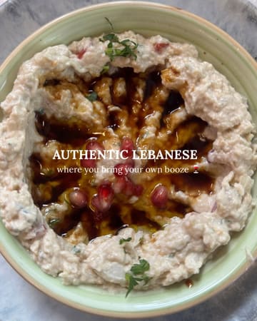 A top-down, close-up shot of a Lebanese dip, likely baba ganoush or mutabal, served in a bowl and garnished with pomegranate seeds and a drizzle of oil. The image features a text overlay highlighting the venue's authentic Lebanese cuisine and BYO policy.