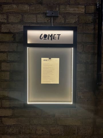 A clean, well-composed, and functional shot of a restaurant menu board mounted on a brick wall, effectively establishing the venue's identity and setting.