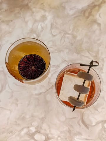 An overhead shot of two cocktails served on a marble surface, showcasing the presentation of the drinks.