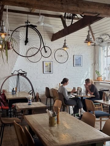 A candid interior shot of a cafe in Oxford, showcasing the venue's unique bicycle-themed decor and a relaxed atmosphere with customers seated.