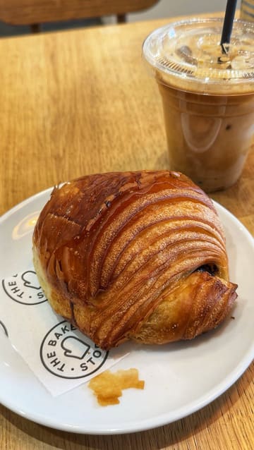 A short, relaxed video showcasing a visit to a bakery, featuring a pan of the pastry display and the creator enjoying a coffee and pastry.