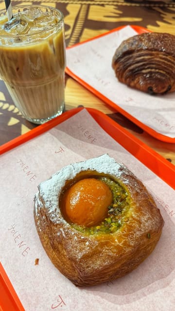The video features a montage of various pastries, breads, and cakes in a display case at Jolene bakery, followed by a shot of the creator eating a pastry and drinking coffee, set to music with text overlays.