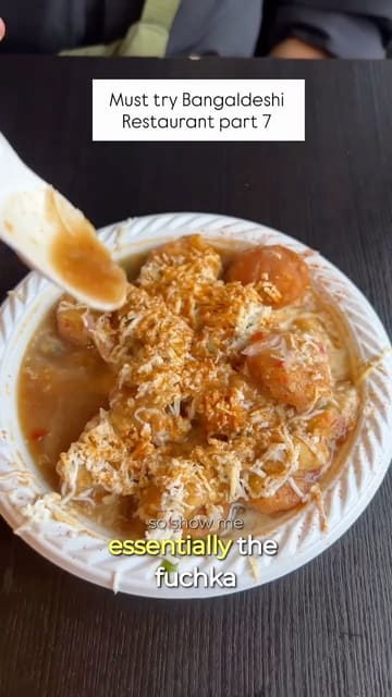A vlog-style review of a Bangladeshi street food venue in East London, featuring various authentic dishes like fuchka, beef seekh kebabs, lassi, and tehari.