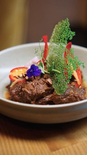 A high-quality, visually focused food showcase of Toba, an Indonesian restaurant in London, featuring close-up shots of various dishes like satay, rendang, and desserts.