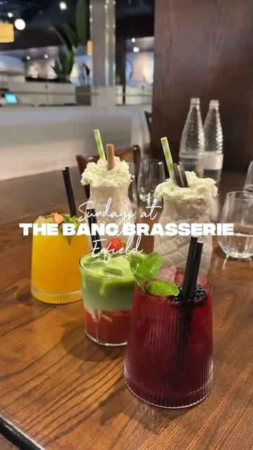 A promotional video for The Banc Brasserie in Enfield, showcasing their Sunday roast menu and signature dishes like mac & cheese and apple crumble French toast. The video features high-quality, slow-motion food shots including gravy and custard pours, set to music with text overlays providing location details.