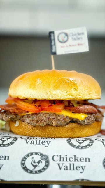 A creator visits the newly opened Chicken Valley in Lansdowne, Bournemouth. The video features a tour of the kitchen, showing the preparation of fried chicken, a smash burger, and Korean wings, followed by a review of the final dishes.