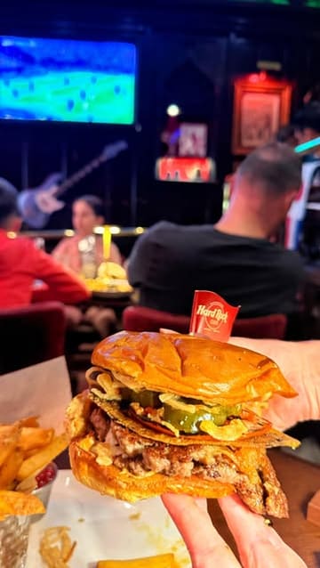A creator visits the Hard Rock Cafe in London to experience a World Cup watch party. The video features shots of the venue's 'The Back Room', the football match on screens, the crowd atmosphere, and close-ups of the food and drinks, specifically highlighting the Messi burger.