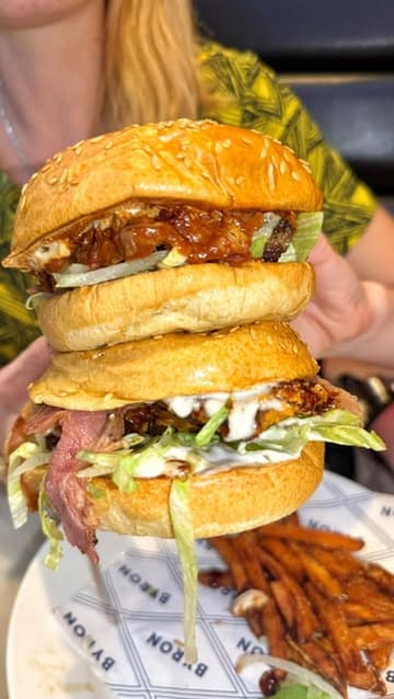 A short, punchy review of a visit to Byron Burgers, featuring close-ups of their loaded burgers, poutine fries, and desserts, alongside shots of the venue's interior.