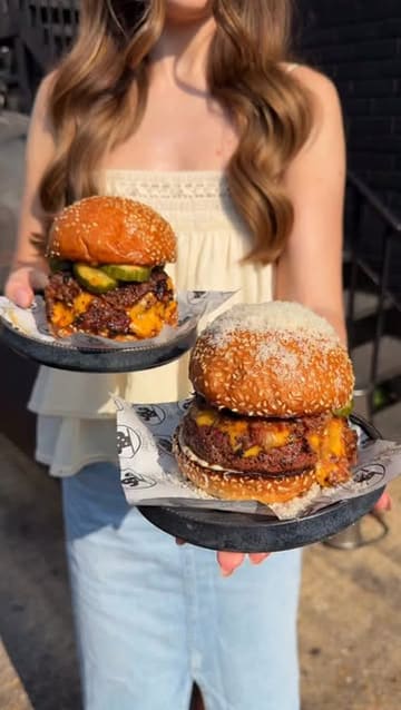 A fast-paced listicle video featuring three burger restaurants in London. The creator introduces each spot, shows close-ups of the burgers being cut and eaten, and provides brief commentary on the food quality and specific menu items.