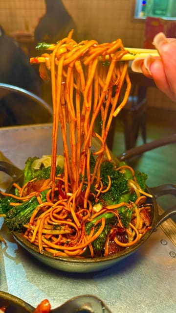 A short, energetic reel showcasing a visit to Man's Market. The video follows the creator entering the venue, demonstrating the unique ordering system where customers write their choices on a card and peg it up, and then presents a variety of Chinese dishes including noodles, gyoza, and bao buns.