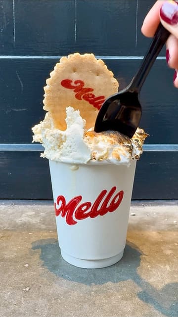 A short, polished video showcasing the preparation of a decadent hot chocolate at Mello, featuring close-up shots of the drink being poured, topped with marshmallow, and torched.