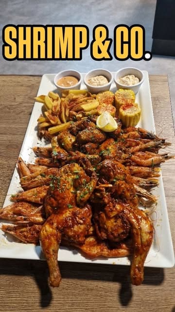 A review of a new seafood restaurant called Shrimp & Co, featuring a large seafood platter, drinks, and the unique experience of wearing bibs and gloves to eat.