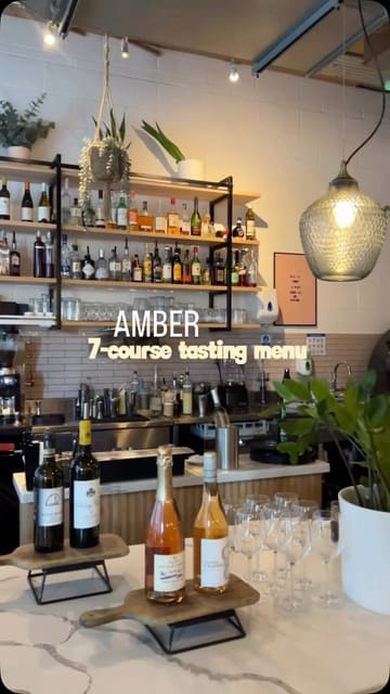 A visually appealing reel showcasing a 7-course tasting menu at a restaurant called Amber. The video features shots of the interior, the open kitchen, various dishes, and cocktails, set to music with text overlays indicating the menu and price.