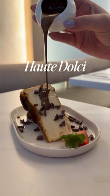 A short, aesthetic reel showcasing various desserts and brunch dishes at Haute Dolci. The video features slow-motion close-ups of chocolate being poured over cheesecake and the Matilda cake, as well as shots of Eggs Benedict and a Lotus Biscoff dessert. The video is set to music and includes text overlays.