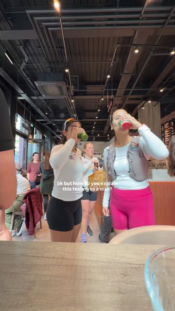 A group of women in athletic wear are filmed during a morning run and subsequent social gathering at a cafe, where they enjoy green juices and cookies. The video focuses on the camaraderie and the 'day in the life' experience of a running club.