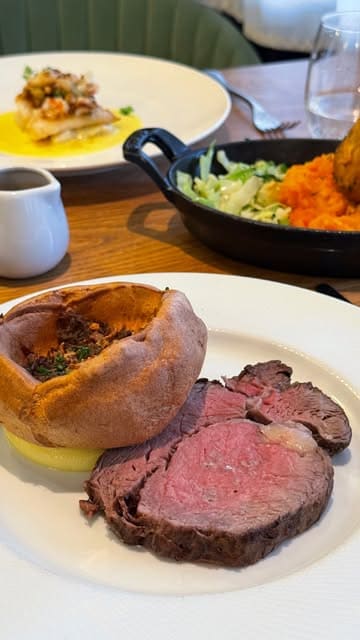 A polished, aesthetic montage showcasing a Sunday lunch experience at Thomas Brasserie, featuring close-ups of roast beef, fish dishes, desserts, and cocktails, alongside shots of the restaurant interior.