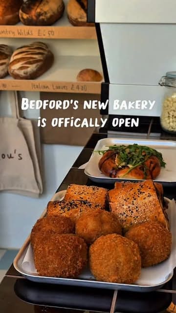 A short, punchy reel showcasing the offerings at a new bakery called Lou's Bakery in Bedford. The video features close-up shots of various baked goods including sourdough loaves, sausage rolls, toasties, and cookies, interspersed with brief glimpses of the shop's interior and exterior.